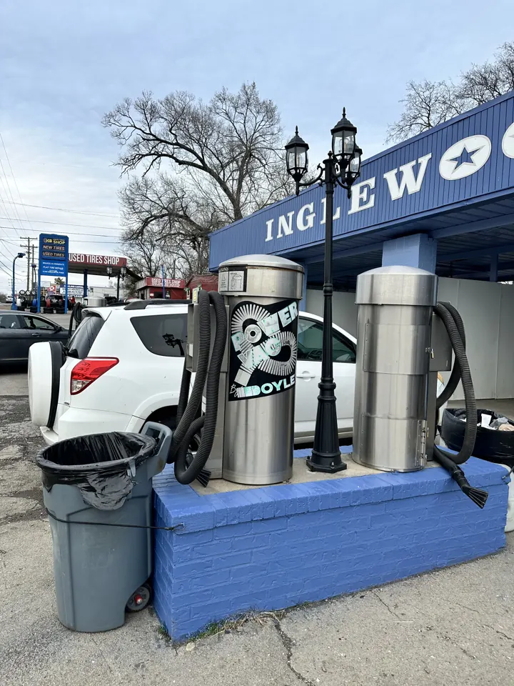 Stainless steel vacuum equipment on a blue base outside Inglewood Autowash.